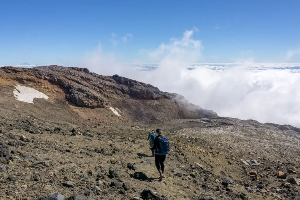 Trampers walking down Mt Ruapehu with cloud building up below