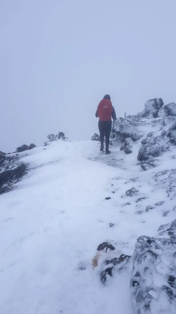 Single tramper walking up snow and ice on the Tongariro Crossing in winter