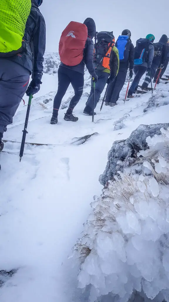 Line of trampers climbing up snow- and ice-incrusted stairs on the Tongariro Crossing in winter