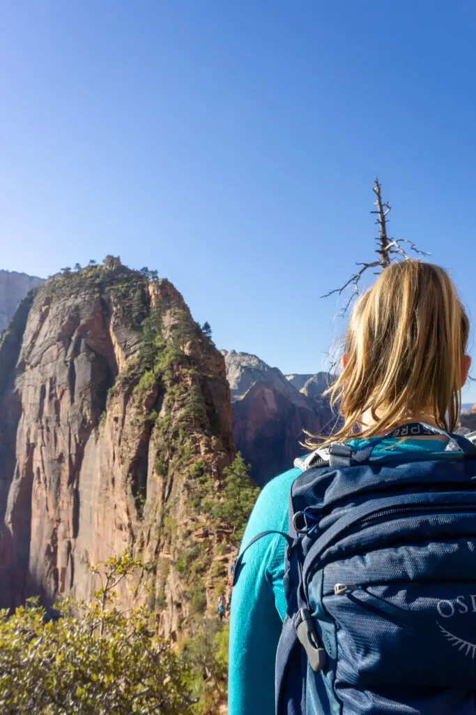 Female hiker wearing a backpack looking across at Angels Landing in Zion National Park