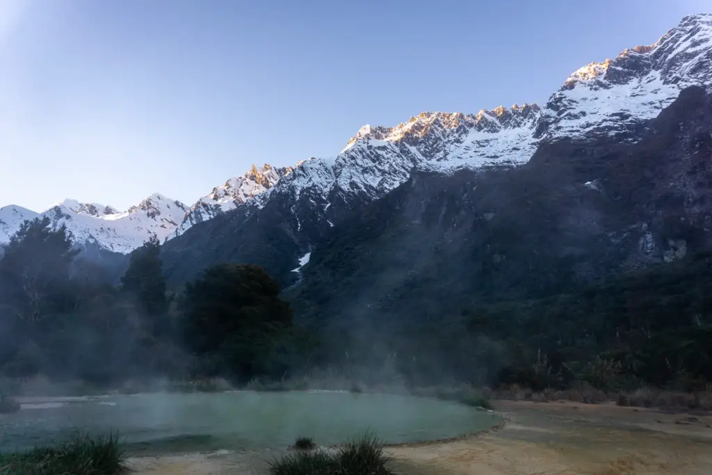 Welcome Flat natural hotpools steaming with dawn light just hitting the tops of the snowcapped mountains in the background
