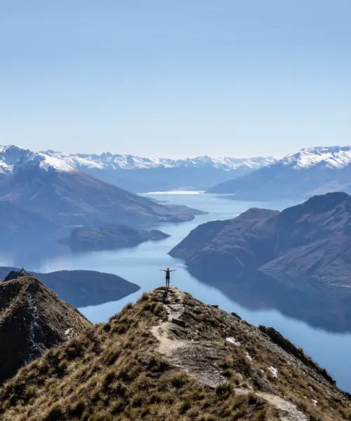"That shot" of Roy's Peak viewpoint with a person standing silhouetted against the reflective lake with arms held up