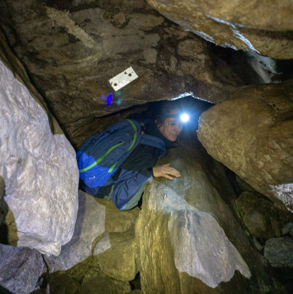 Lady squeezing through a tight rock passage in the Clifden Caves