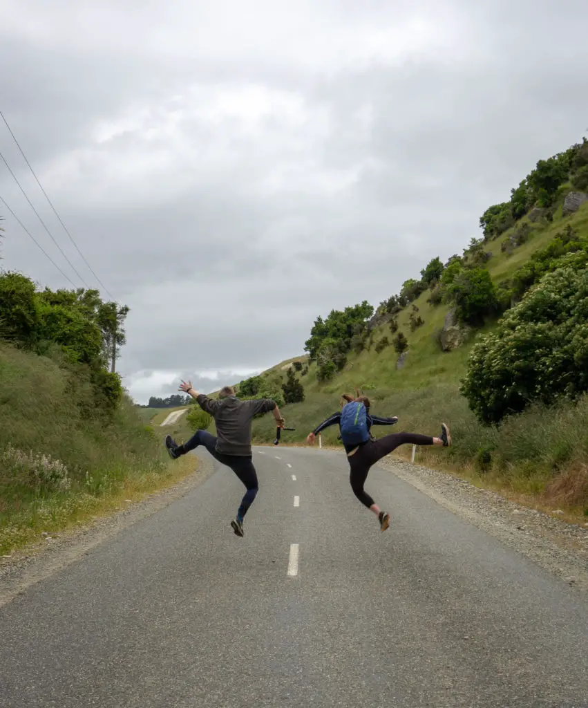 Two people jumping in middle of a road