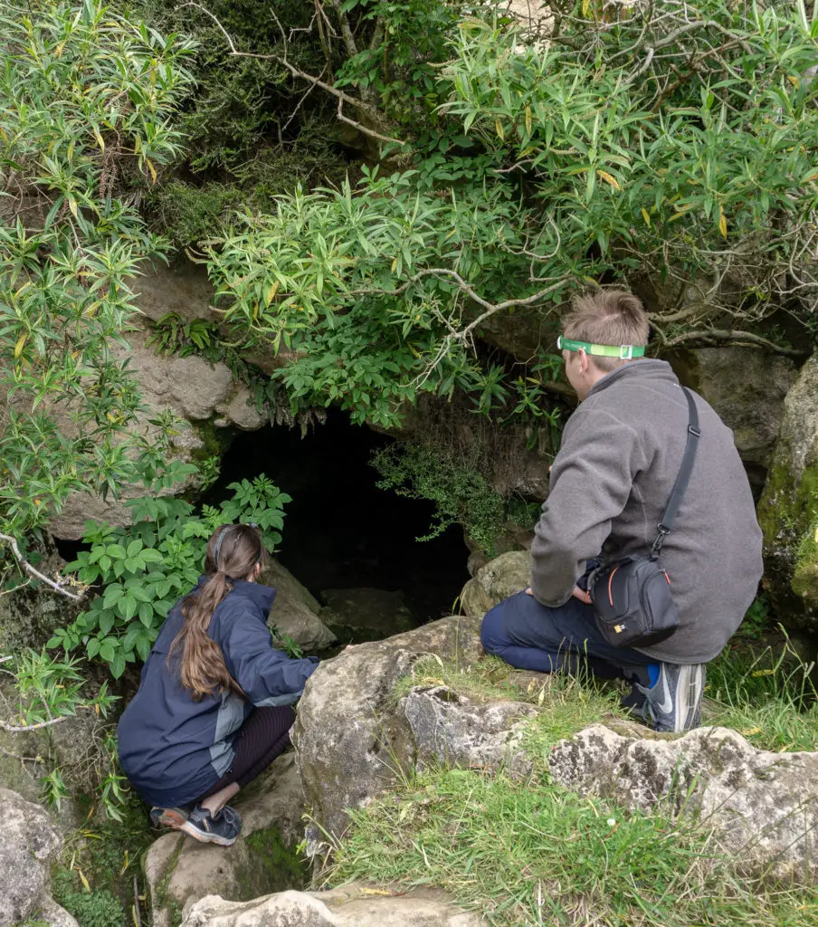 Two people looking into the entrance of the Clifden Caves
