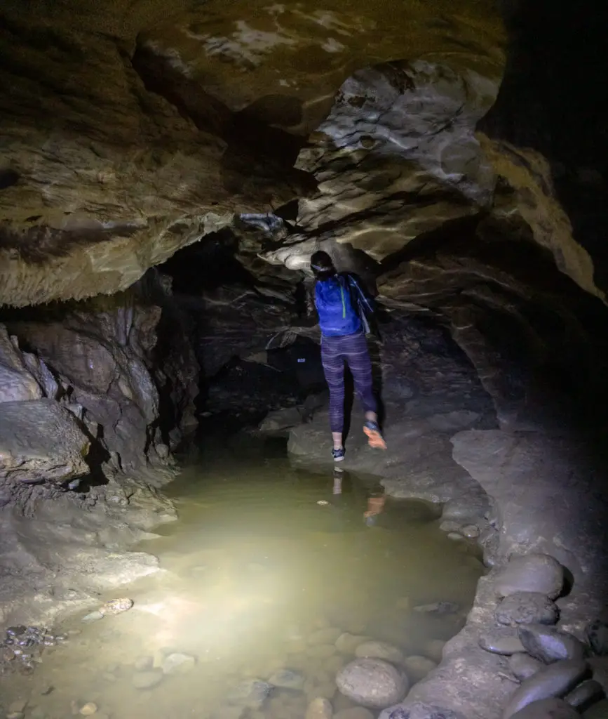 A person climbing around a pool of water in the Clifden Caves