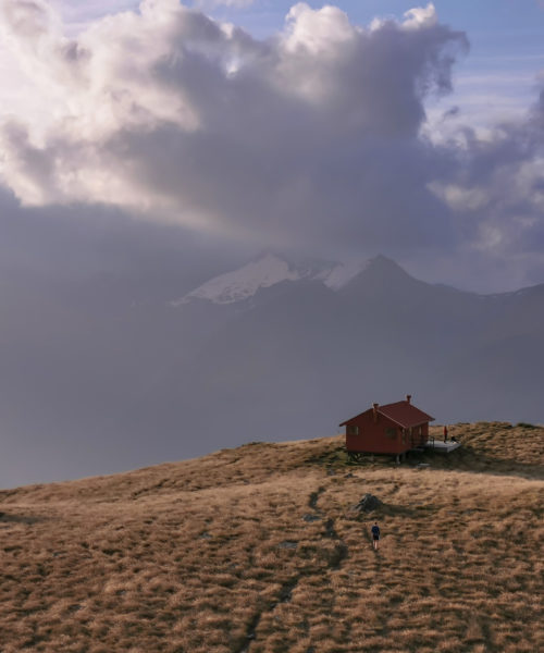 Brewster Hut at dusk, with purple-blue haze from the Australian bushfire almost hiding the mountains in the background