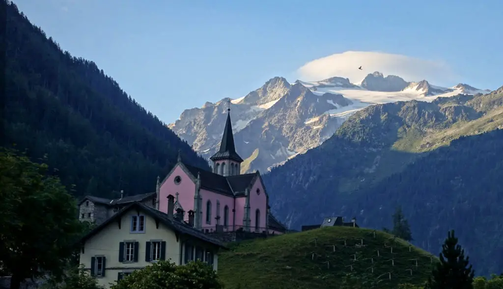 View of a pink church in the Dolomites, Italy with mountains in the background