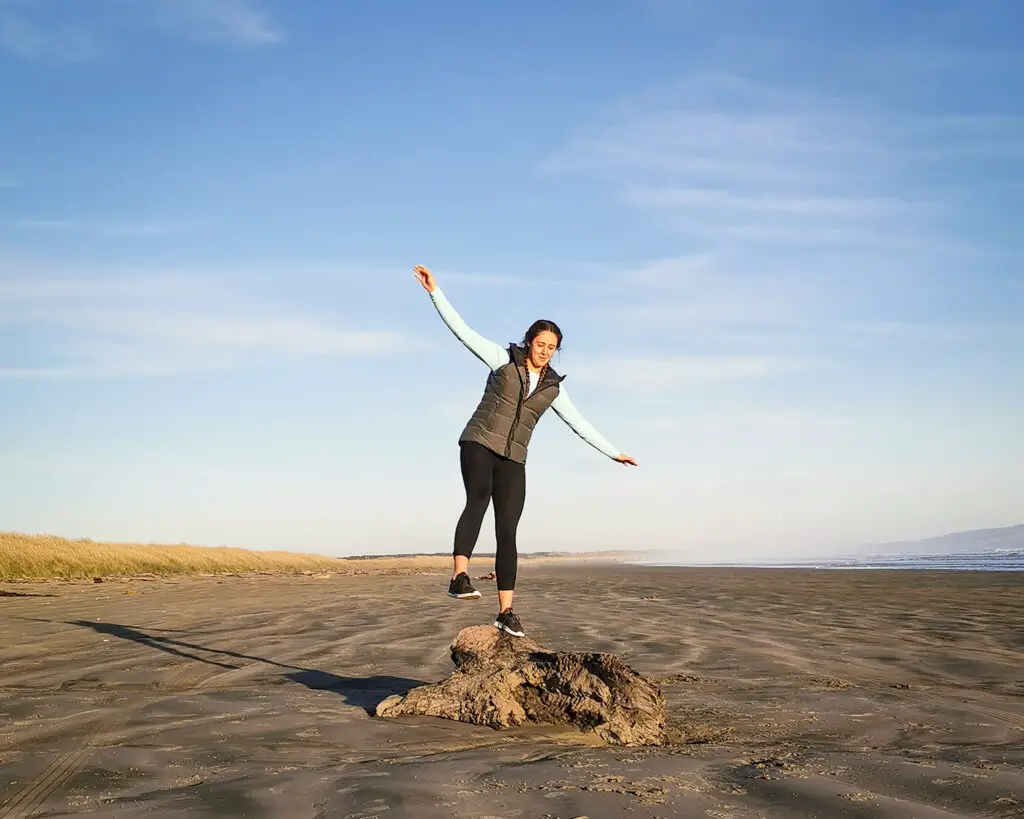 Girl balancing on a piece of drift wood on a beach