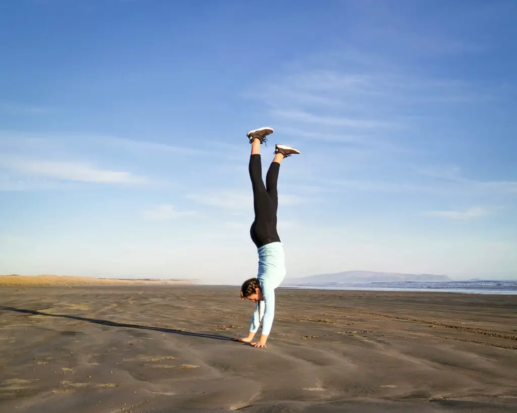 Girl doing a handstand on a beach