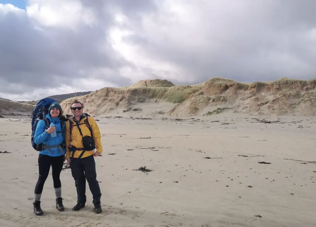 Two hikers looking clean and happy at Mason Bay at the start of their tramping trip