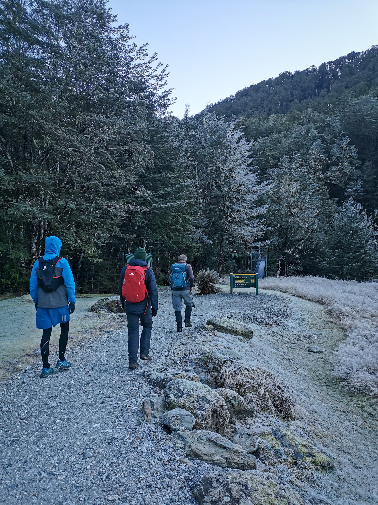 Group of trampers setting out along the Routeburn Great Walk with frosty trees and ground