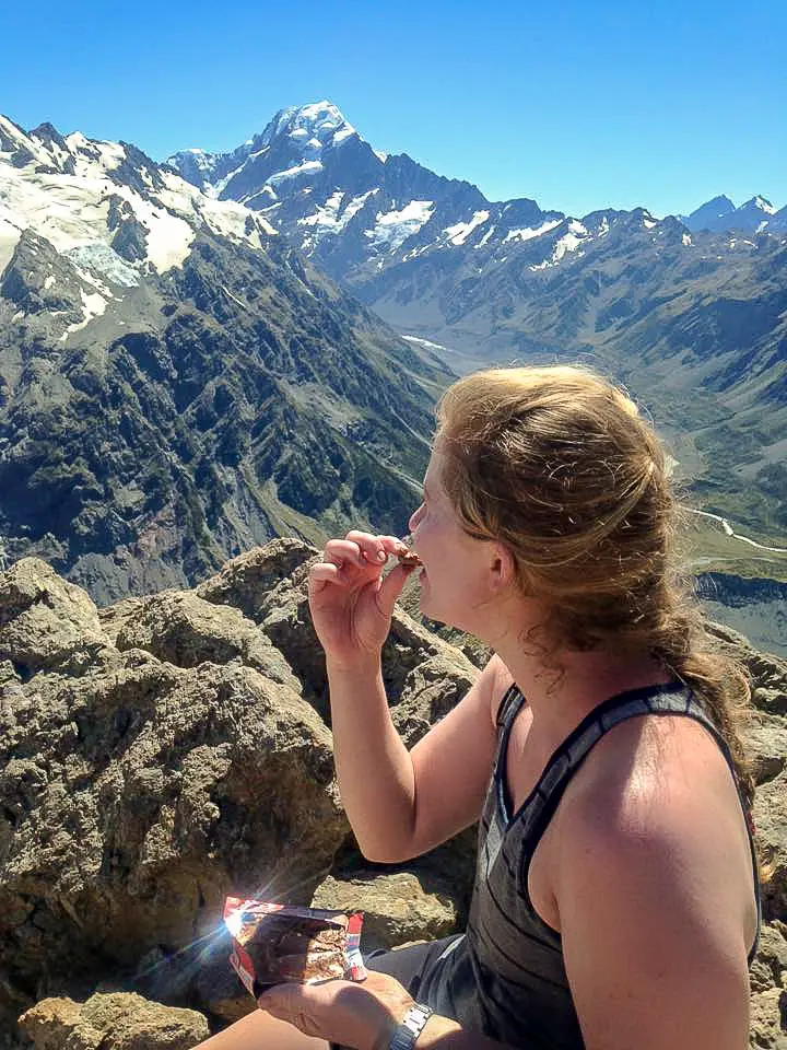 Lady eating a melted chocolate bar with Aoraki / Mt Cook in the background