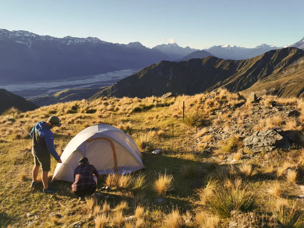 Setting up a tent just below Heather Jock Hut as the sun sets on the surrounding mountains