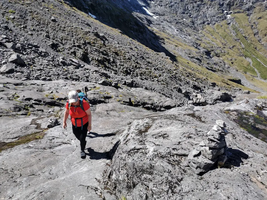 Female hiker climbing up rock slabs on the Gertrude Saddle route