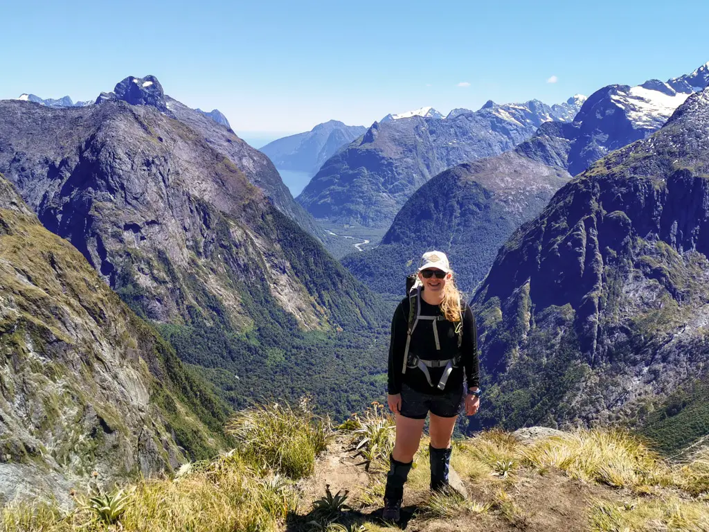 Female hiker on top of Gertrude Saddle with views back to Milford Sound in Fiordland National Park