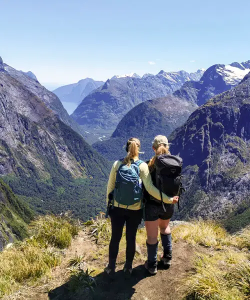 Two female hikers looking out at the view over Milford Sound from Gertrude Saddle in Fiordland National Park