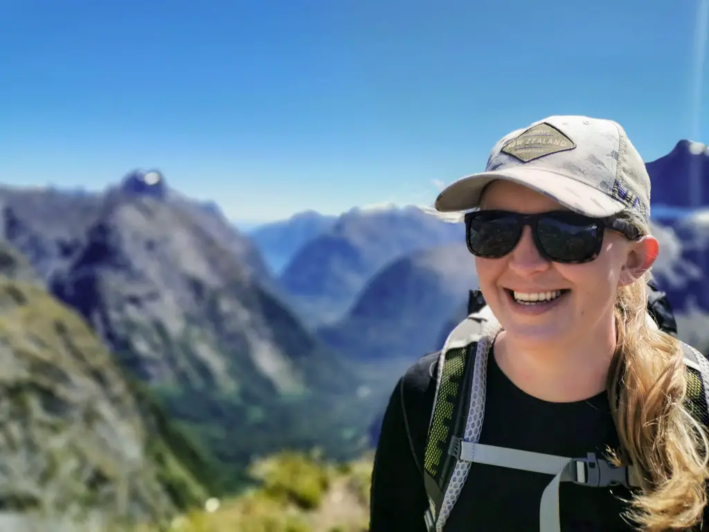 Female hiker on the top of Gertrude Saddle with views to Milford Sound behind