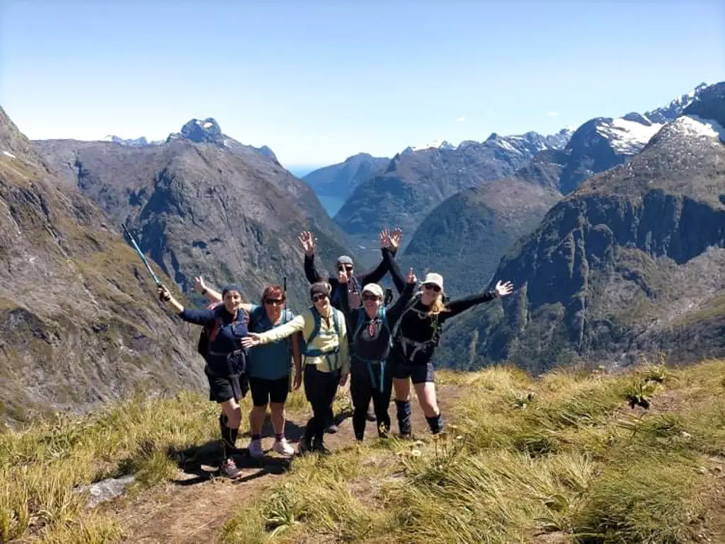 Group of trampers at the top of Gertrude Saddle in Fiordland National Park with Milford Sound and the Tasman Sea behind