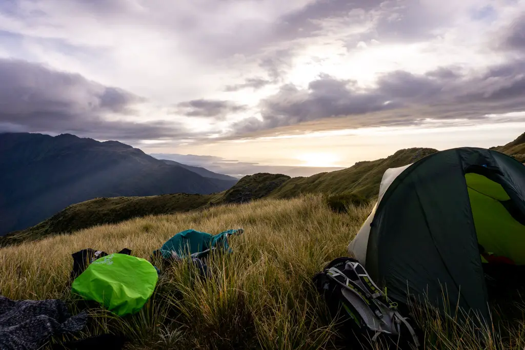 Tent and gear spread out over tussocks at sunset