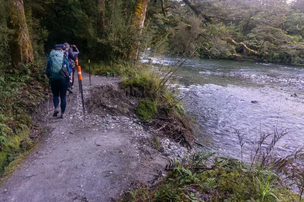 Hikers walking past flood damage on the Milford Track next to the Clinton River