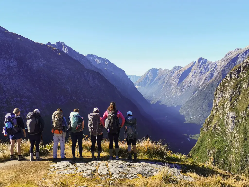Group of hikers standing on top of McKinnon Pass looking out over the Clinton Valley on the Milford Track