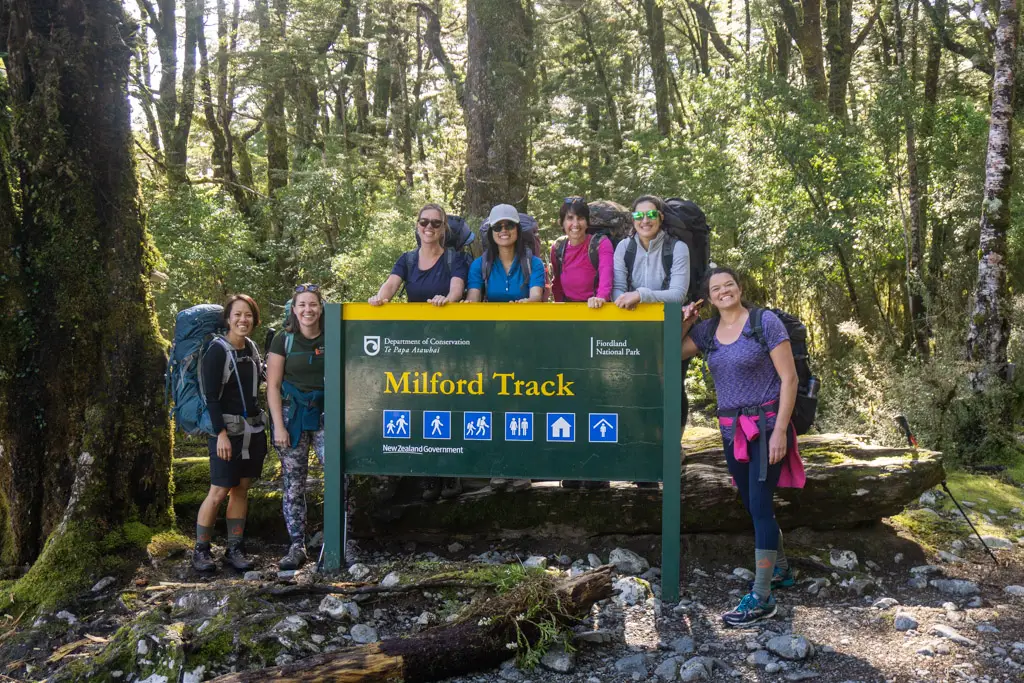 Group of hikers behind the Milford Track sign at the trailhead