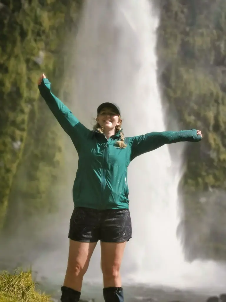 Female hiker, Alice Adventuring, in front of Sutherland Falls on the Milford Great Walk