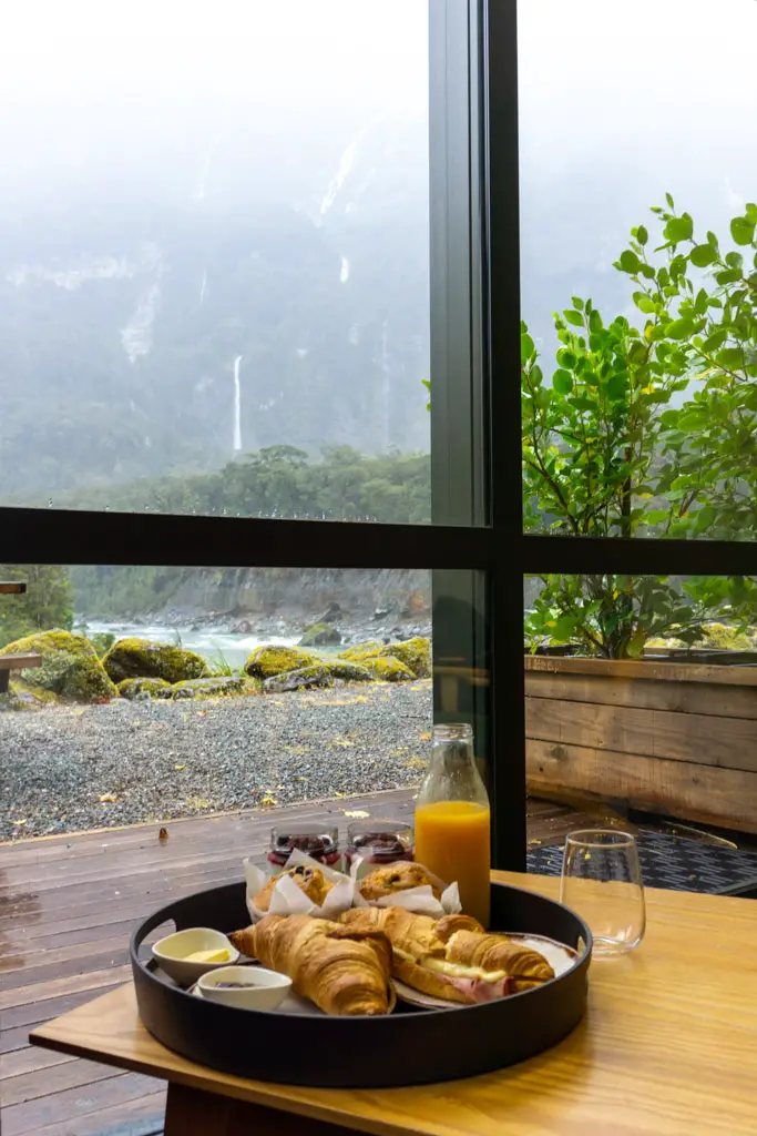Continental breakfast at Milford Sound Lodge with waterfalls through the window in the background