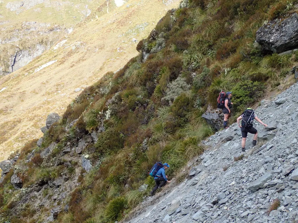 Trampers climbing up a steep slip out of Emily Creek on the way to Emily Pass