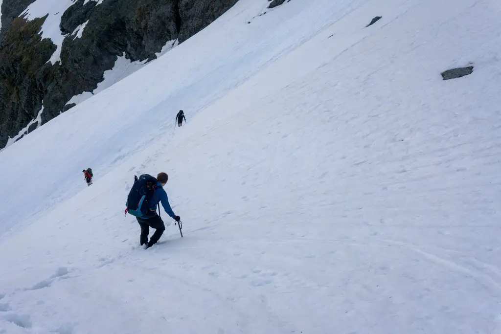 Trampers climbing down steep snow slopes