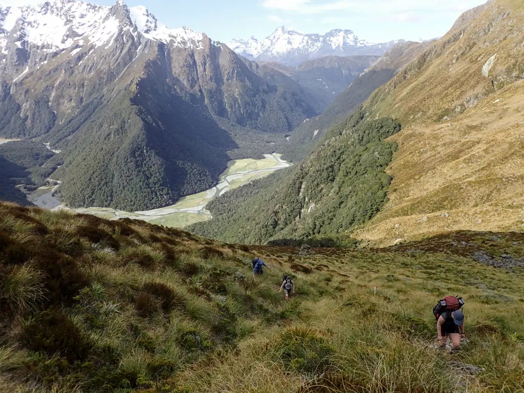Trampers climbing up Emily Pass above Routeburn Flats in the background