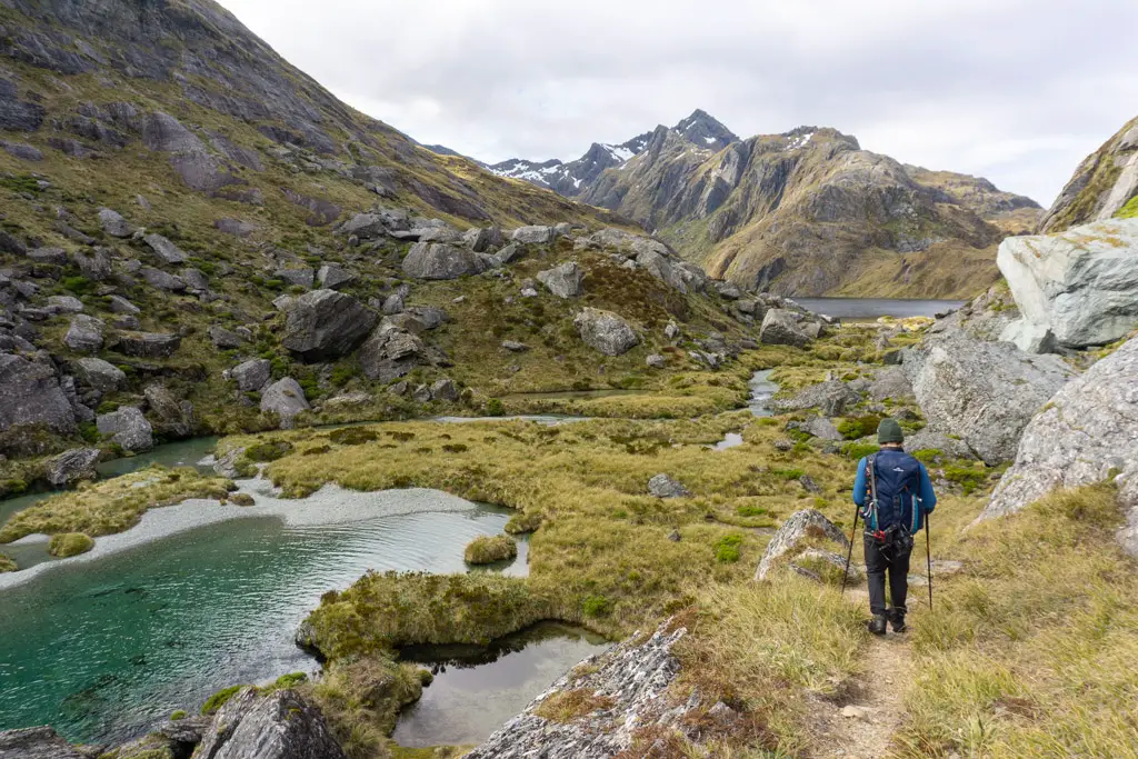 Tramper walking towards Lake Harris and the Routeburn Track from Valley of the Trolls