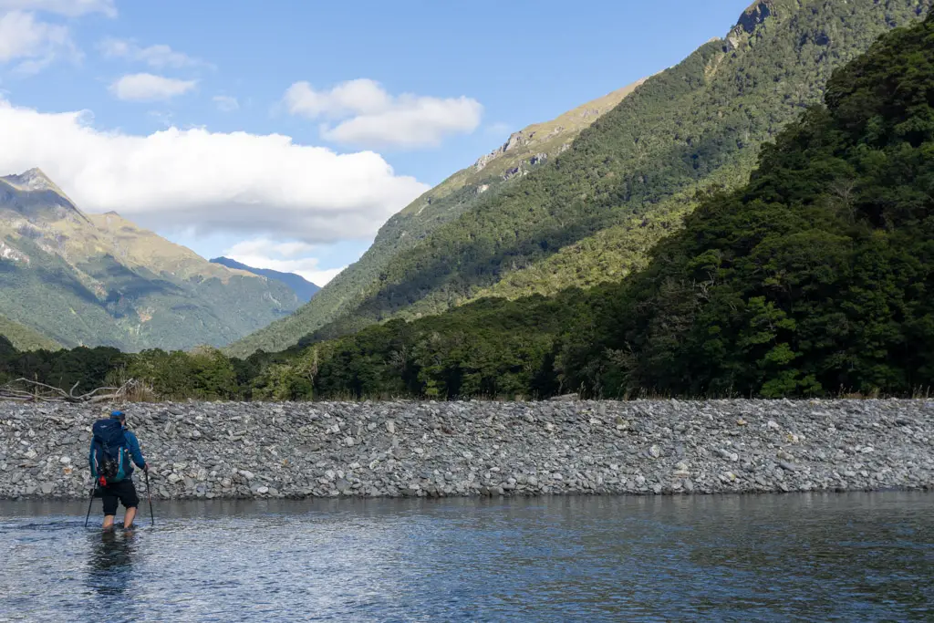 Man crossing the Makarora River towards the Young River at the start of the Wilkin-Young Circuit