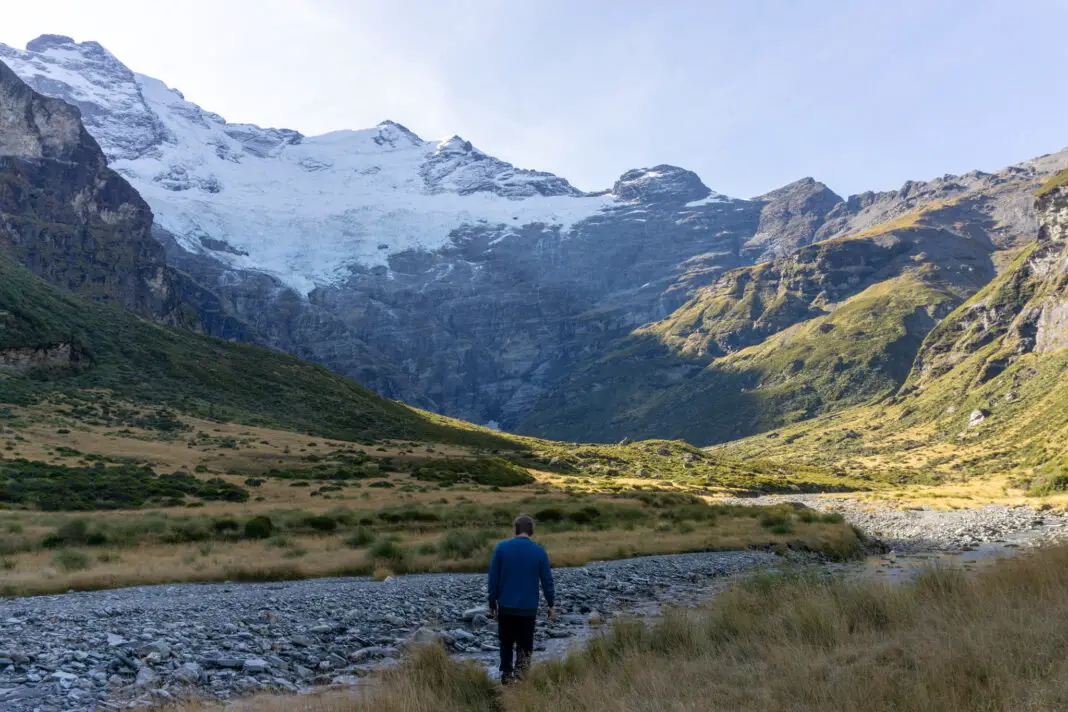 Man walking next to the Earnslaw Burn with Mt Earnslaw and its hanging glaciers in the background