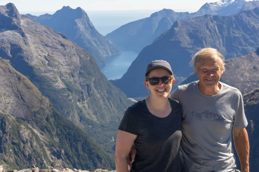 Two happy trampers standing on the summit of Barrier Knob, with Milford Sound in the background