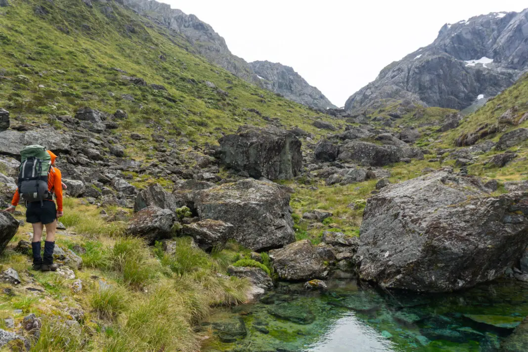 Tramper climbing up to North Col with a green tarn next to him