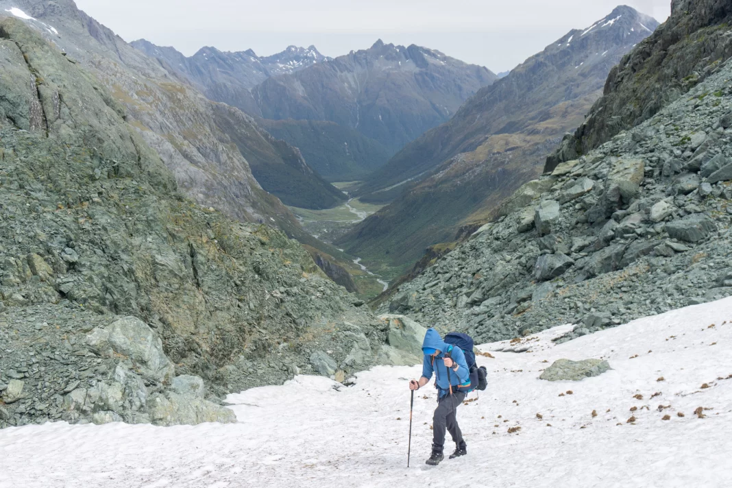 Man climbing up a snow slope to North Col with Routeburn Flats in the background