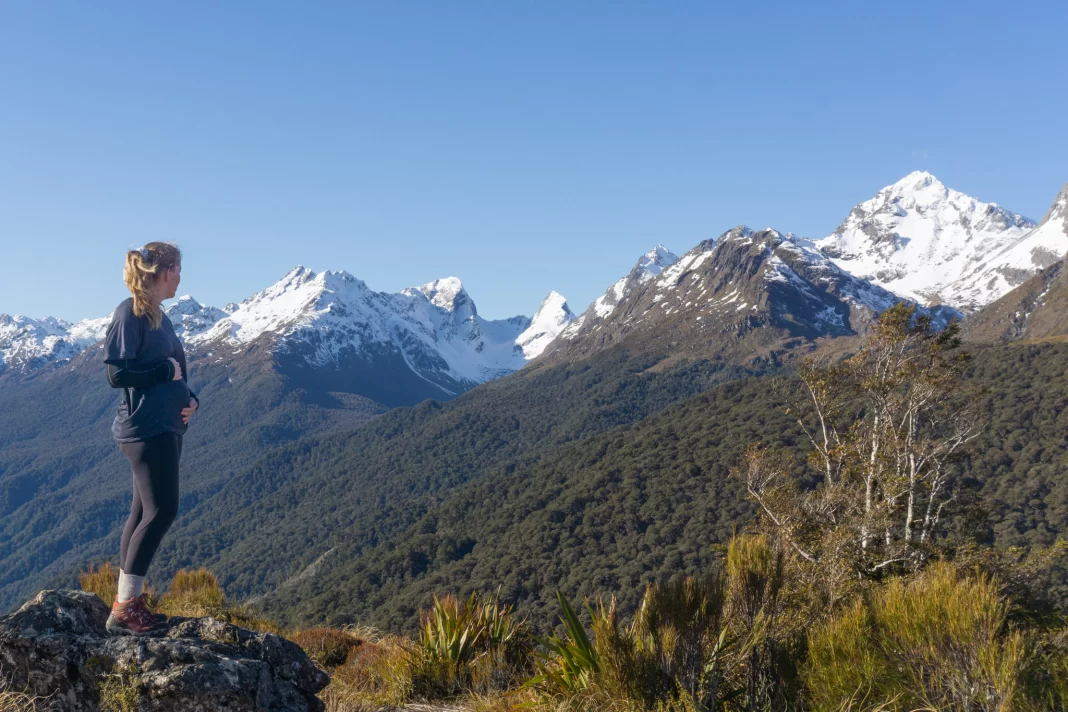 Pregnant woman standing on top of Key Summit with snowy mountains in the background
