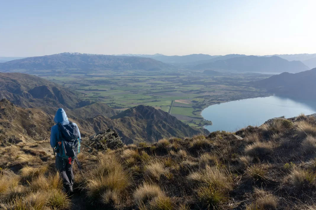 Man climbing down from Breast Hill with Hawea and the lake in the background