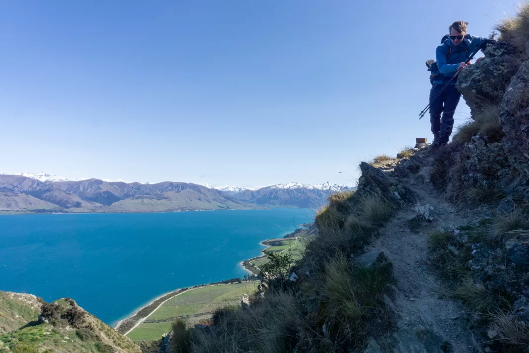 Man climbing down the Breast Hill Track with Lake Hawea in the background