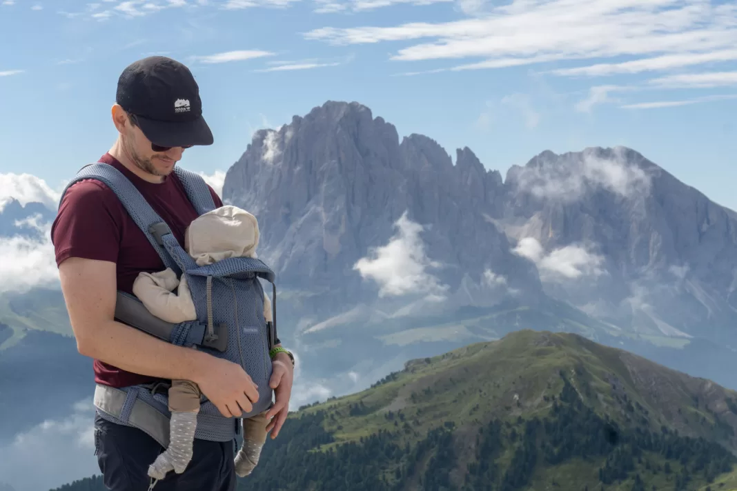 Man holding baby in Seceda, Dolomites with mountains in the background