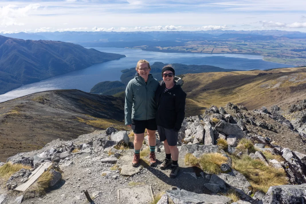 Two women competing in the Summit Challenge, standing on top of Mt Luxmore on the Kepler Track in Te Anau
