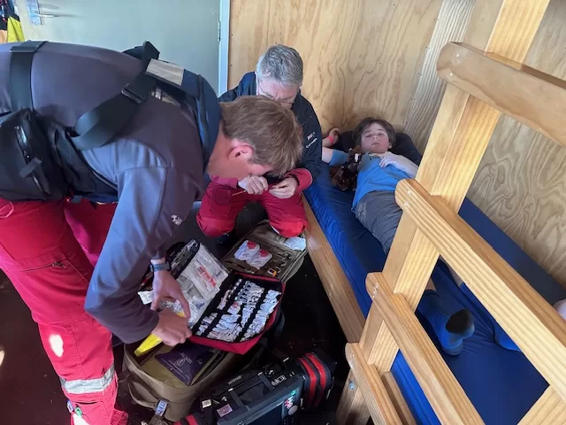 Paramedics assess an injured boy in a DOC hut