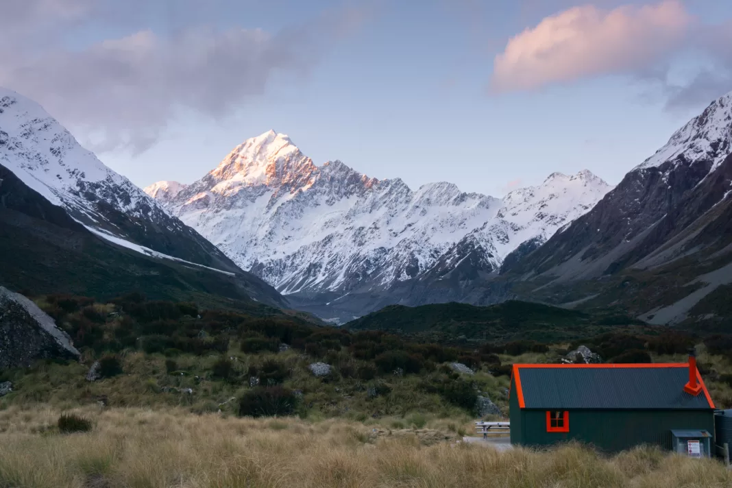 Photo of Hooker Hut with the sun setting on Aoraki Mt Cook