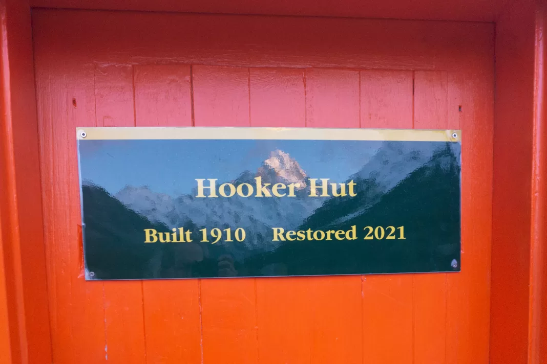 Sign on Hooker Hut with a reflection of Aoraki Mt Cook 