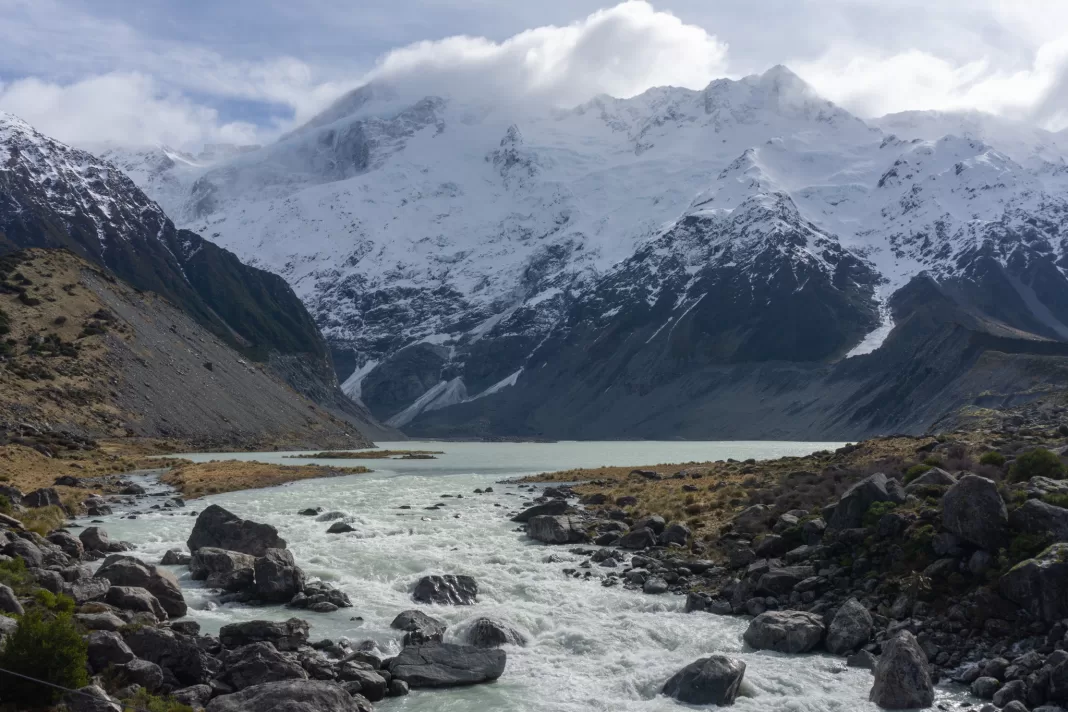 Photo of Mueller Lake with a snowy and cloudy Mt Sefton in the background