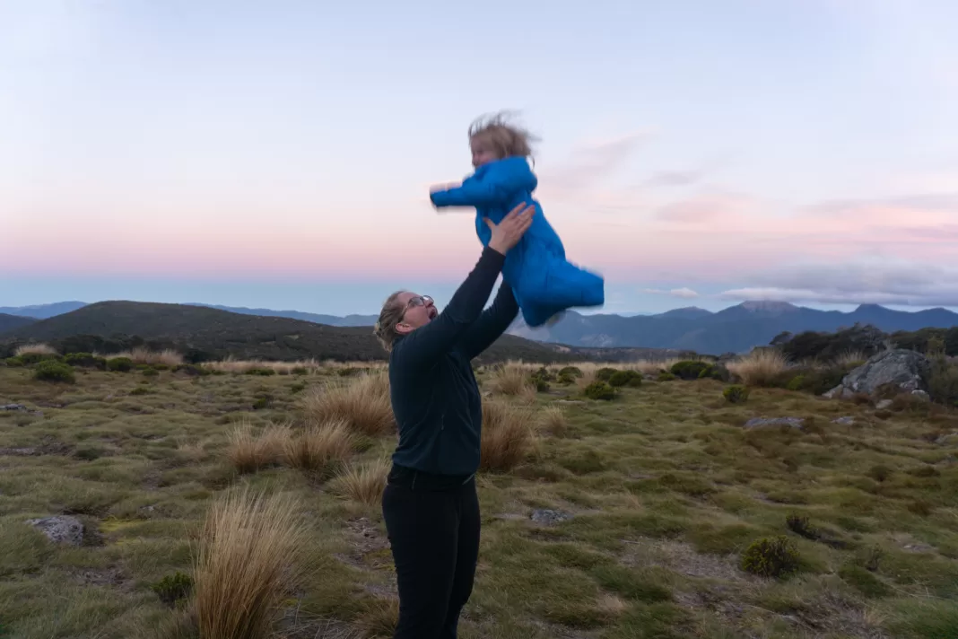 Mum throwing toddler up in the air in the mountains