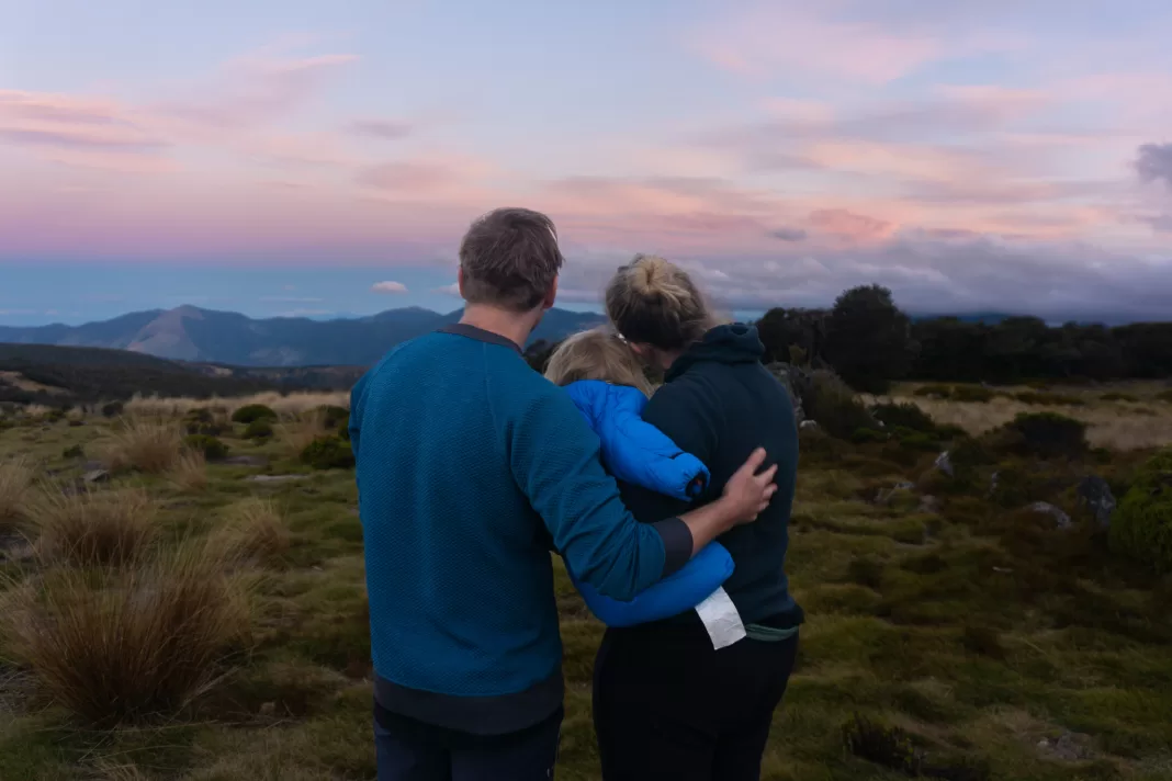 Family looking away from the camera at sunset with a pink sky above the mountains