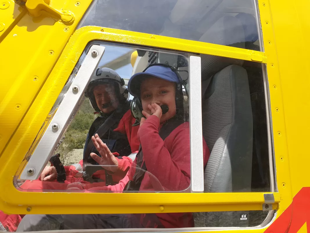 Girl waving through the window of a yellow rescue helicopter